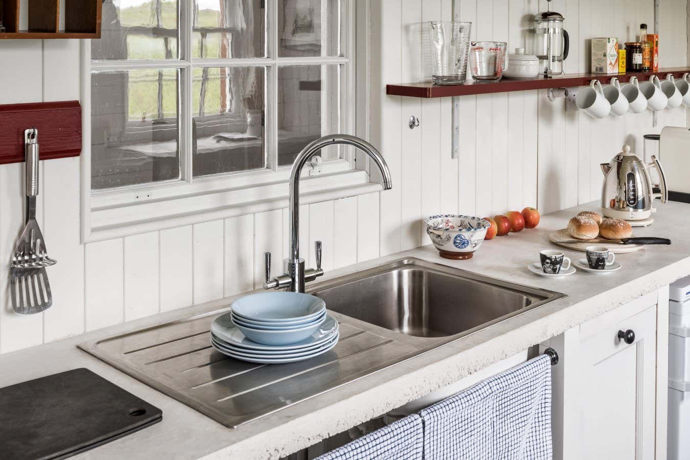 J773YF Kitchenware on shelves with stainless steel sink in 17th century Kintyre stone cottage